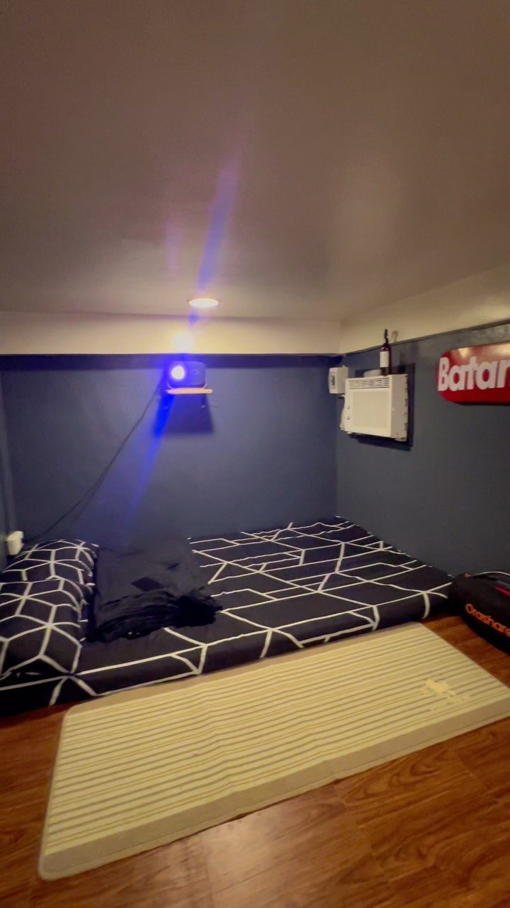 Projector on a shelf casting light over a mattress in a blue room