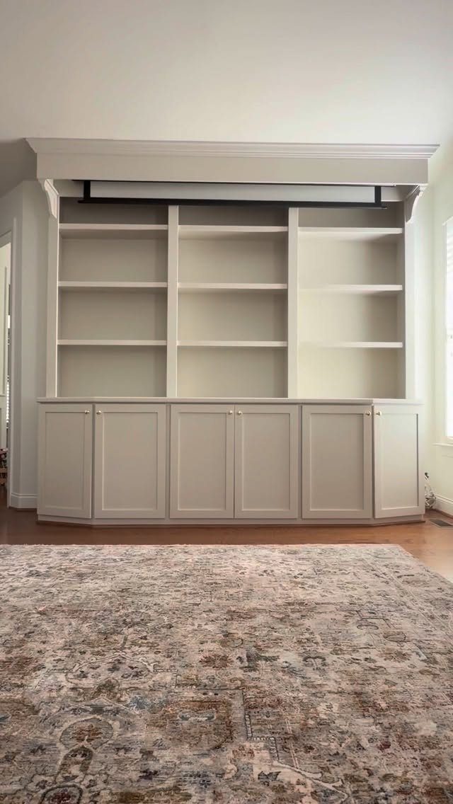 White built-in shelving unit with a retracted pull-down projector screen in the ceiling molding