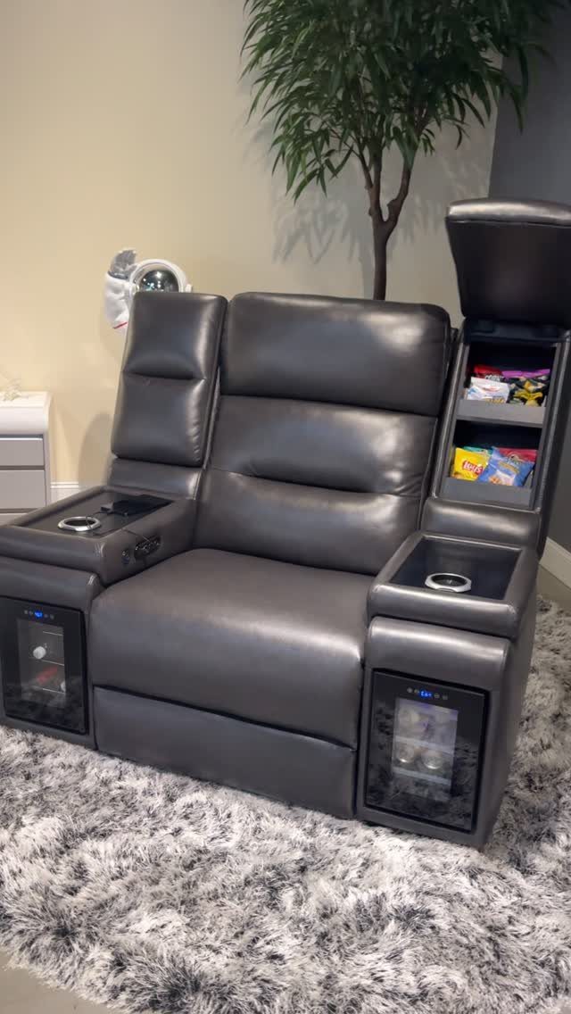 Grey leather reclining theater chair with cup holders and snack storage on shag rug