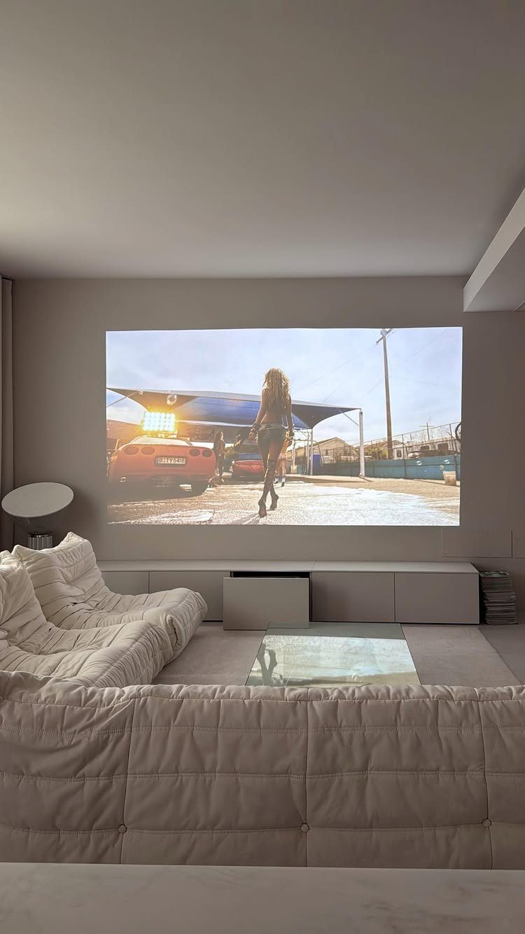 Large projection screen in a modern living room with plush white sectional seating.