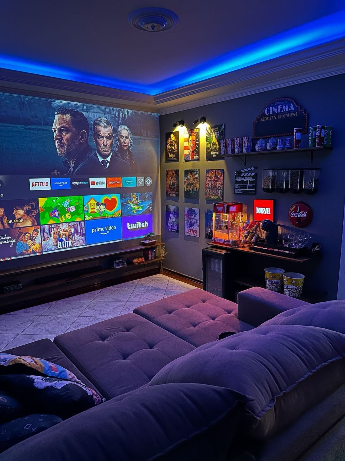 Home theater room with projector screen, purple sectional sofa, and snack station.