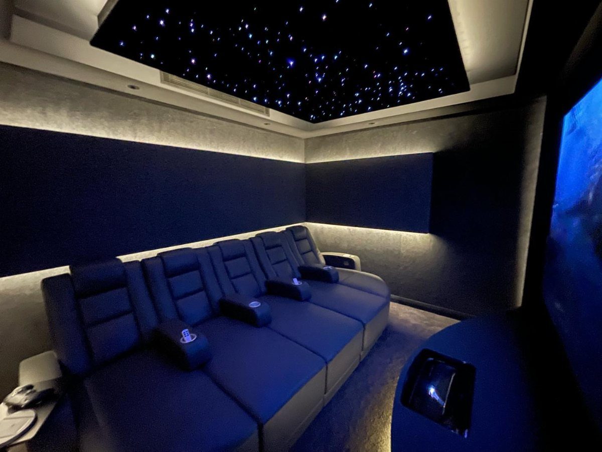 Blue leather reclining seats in a small home theater with a starry ceiling.