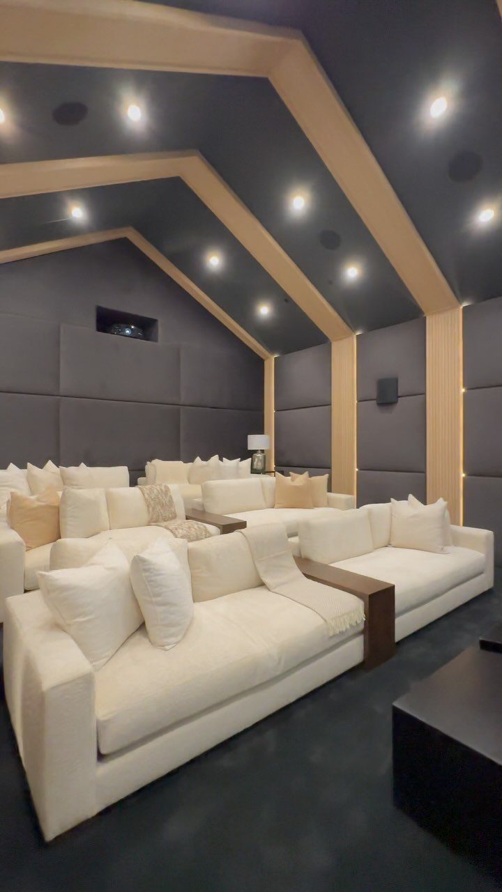White sectional sofas in a media room with grey walls and wood trim.