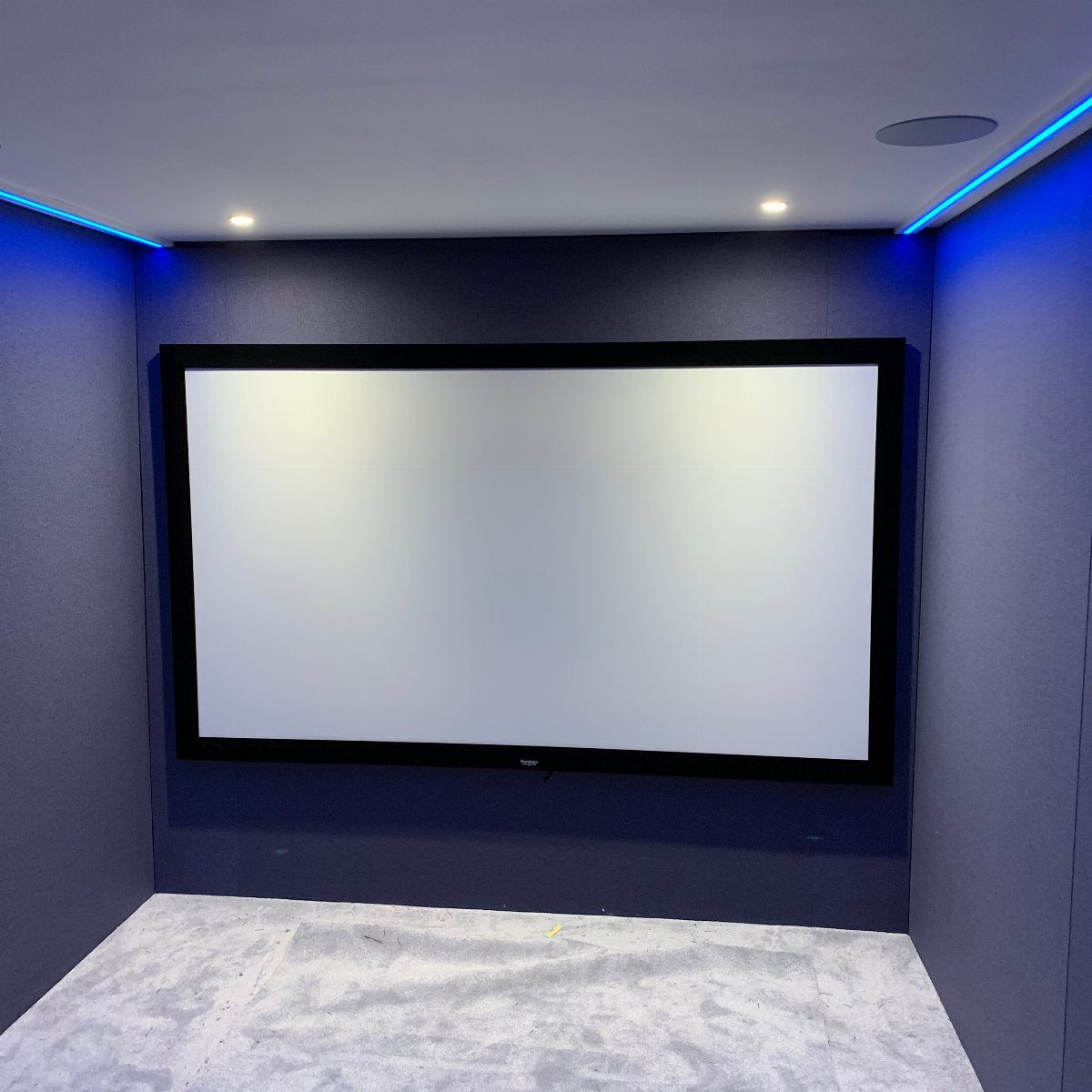 Large projection screen in a small room with purple walls and blue LED lighting