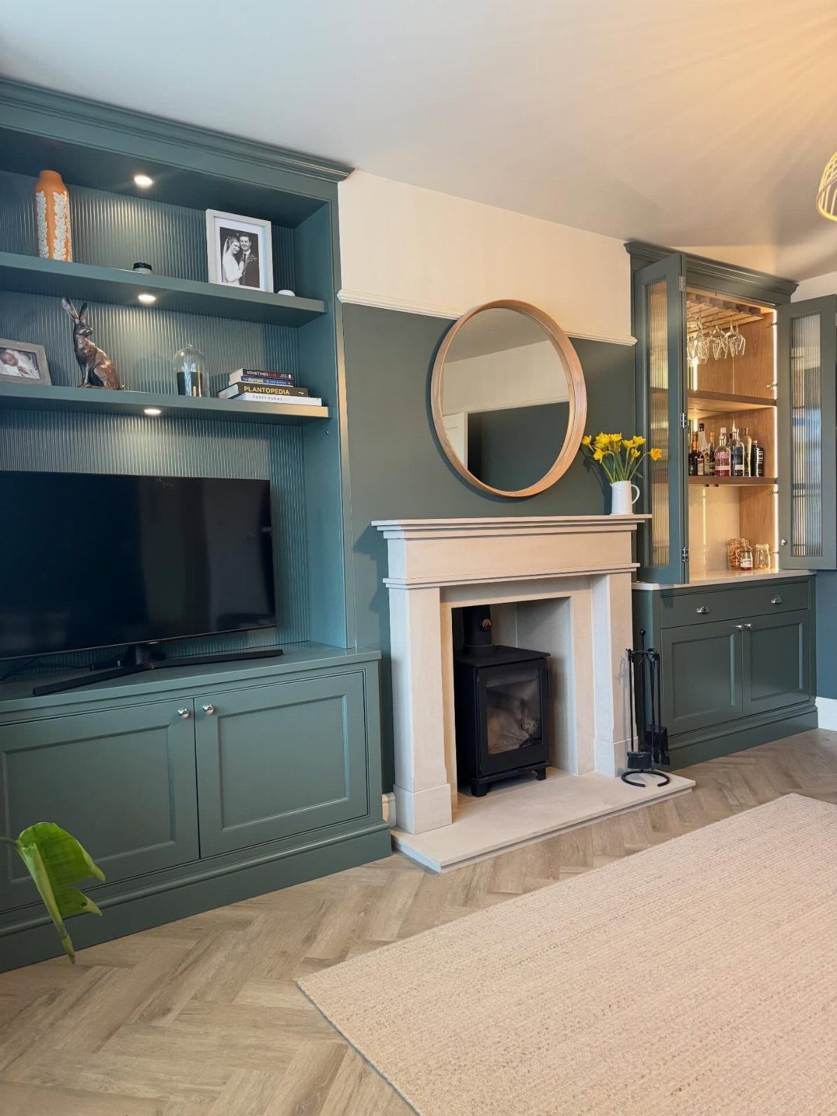Dark green built-in media storage cabinets surrounding a television and a white fireplace.