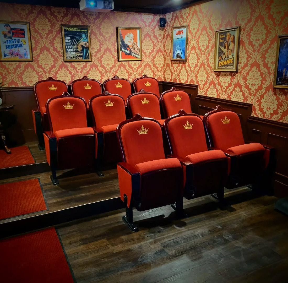 Red velvet cinema seats with gold crowns in a themed home theater room.