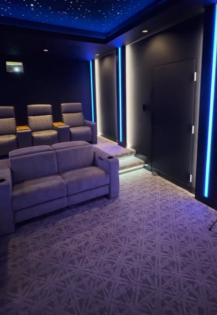 Small home media room with blue LED lighting and grey theater seating.