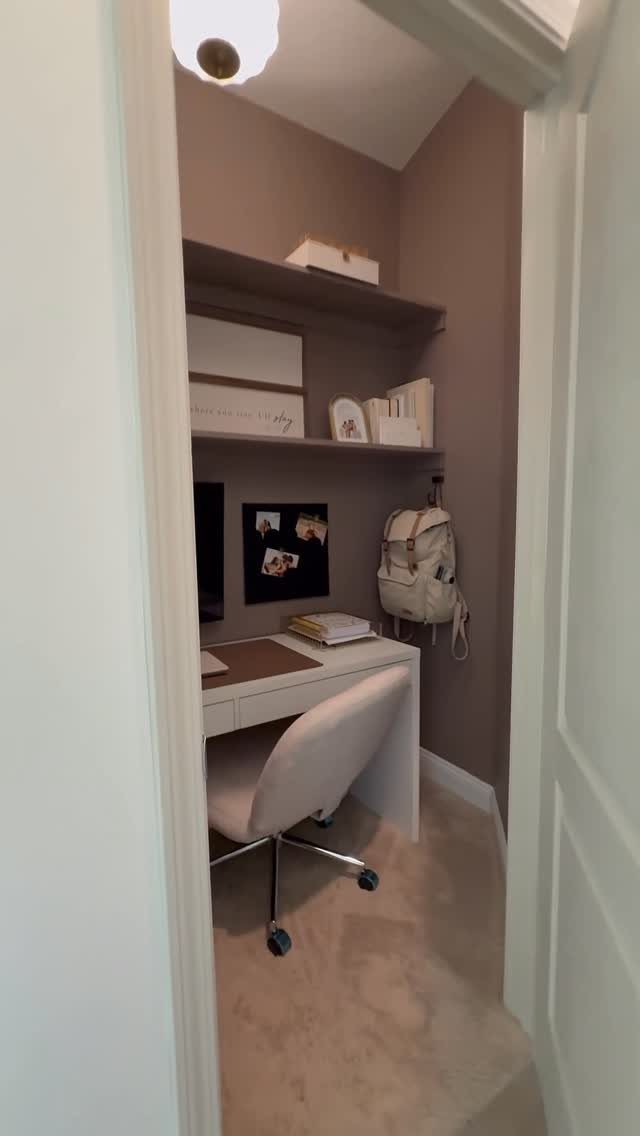 White desk and chair installed inside a small brown closet with overhead shelving.