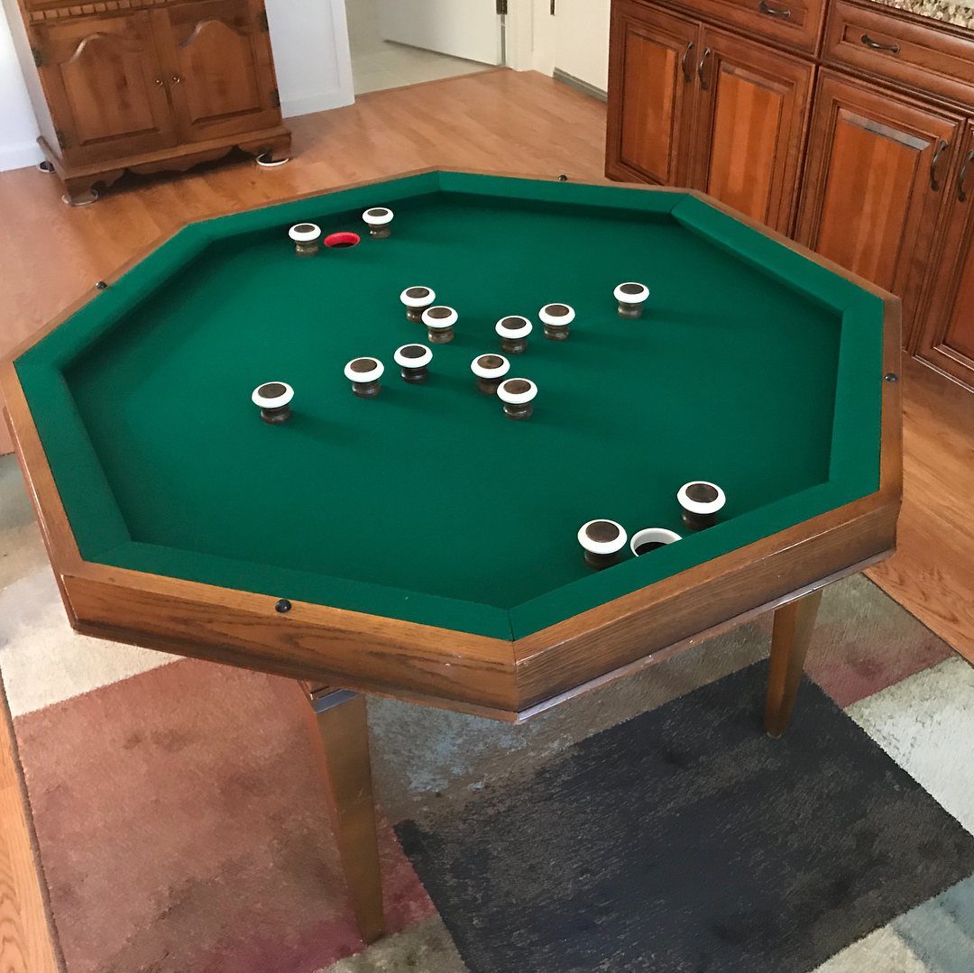 Octagonal bumper pool table with green felt and pucks in a home room.