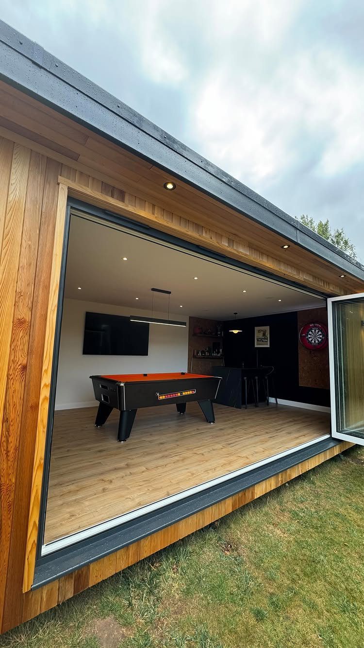 Small pool table with red cloth inside a modern wooden garden room