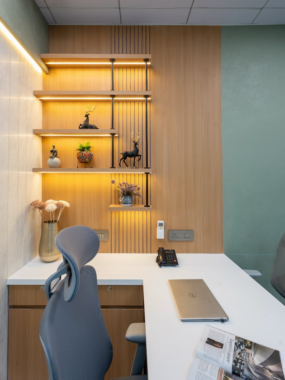 White desk and light wood shelving with warm lighting in a bright office.