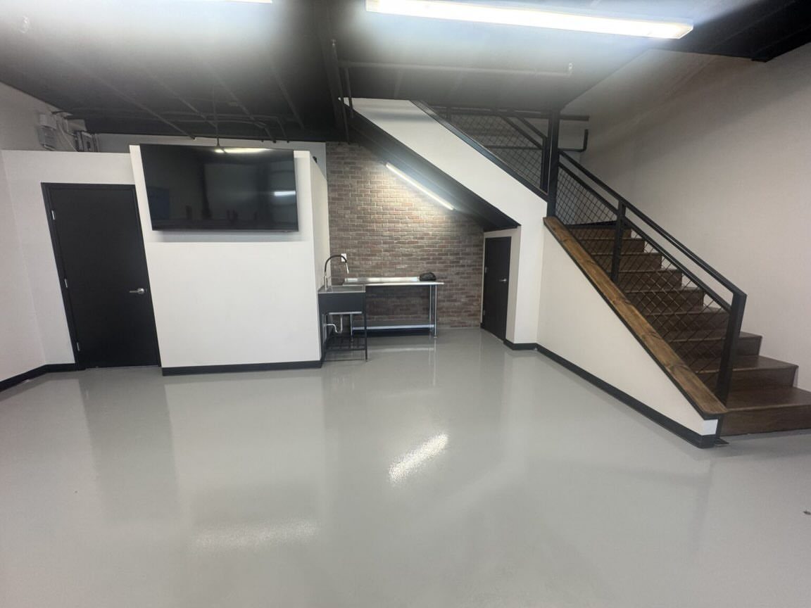 Modern garage interior with a wooden staircase leading to a mezzanine loft level.