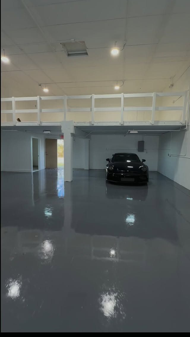 White wooden storage loft platform above a black car in a modern garage