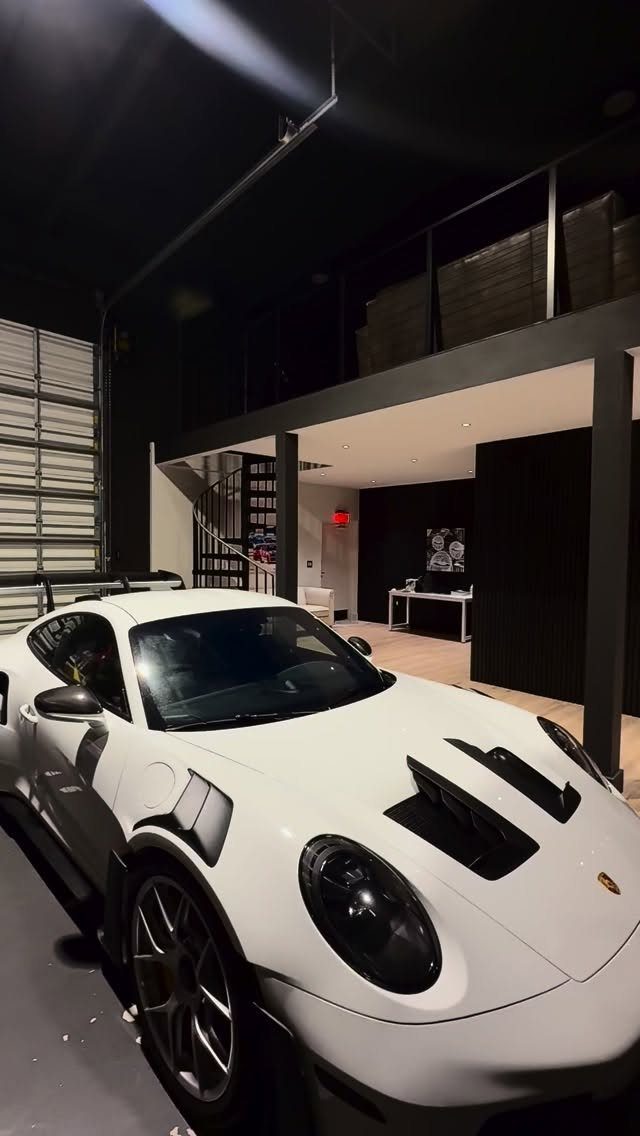 White sports car in a modern garage with a black loft mezzanine above.