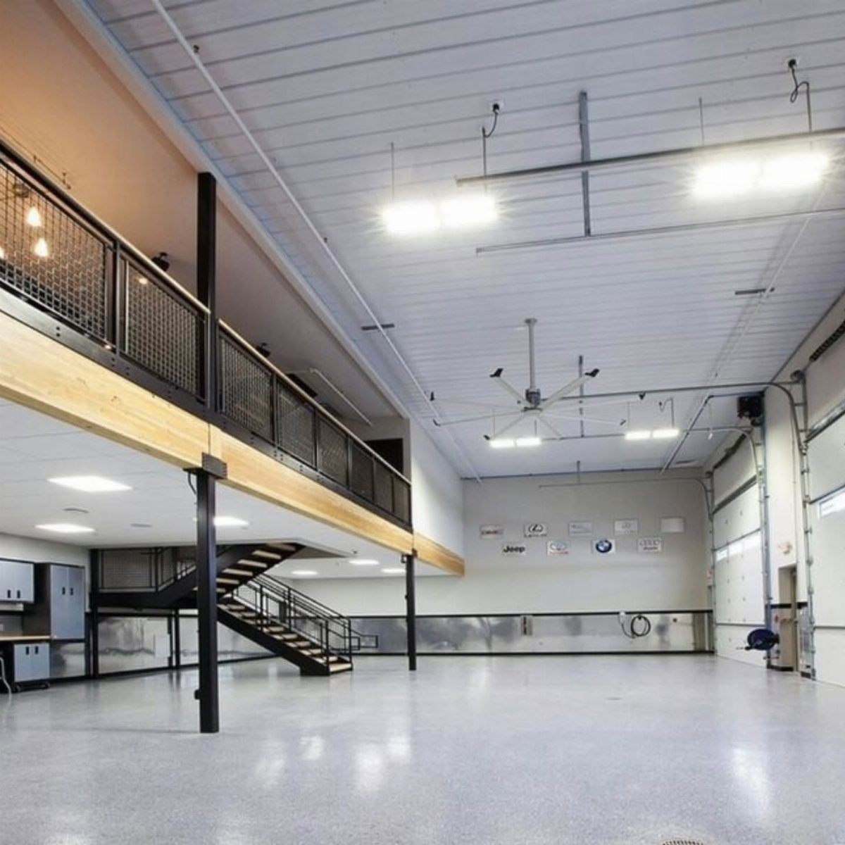 Modern garage interior featuring a mezzanine loft with black railings and stairs.