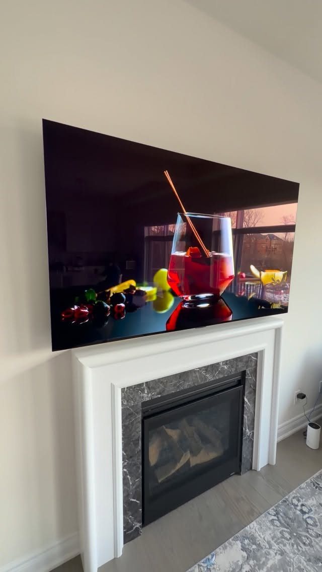Flat-screen television mounted on a white wall above a white fireplace mantel.