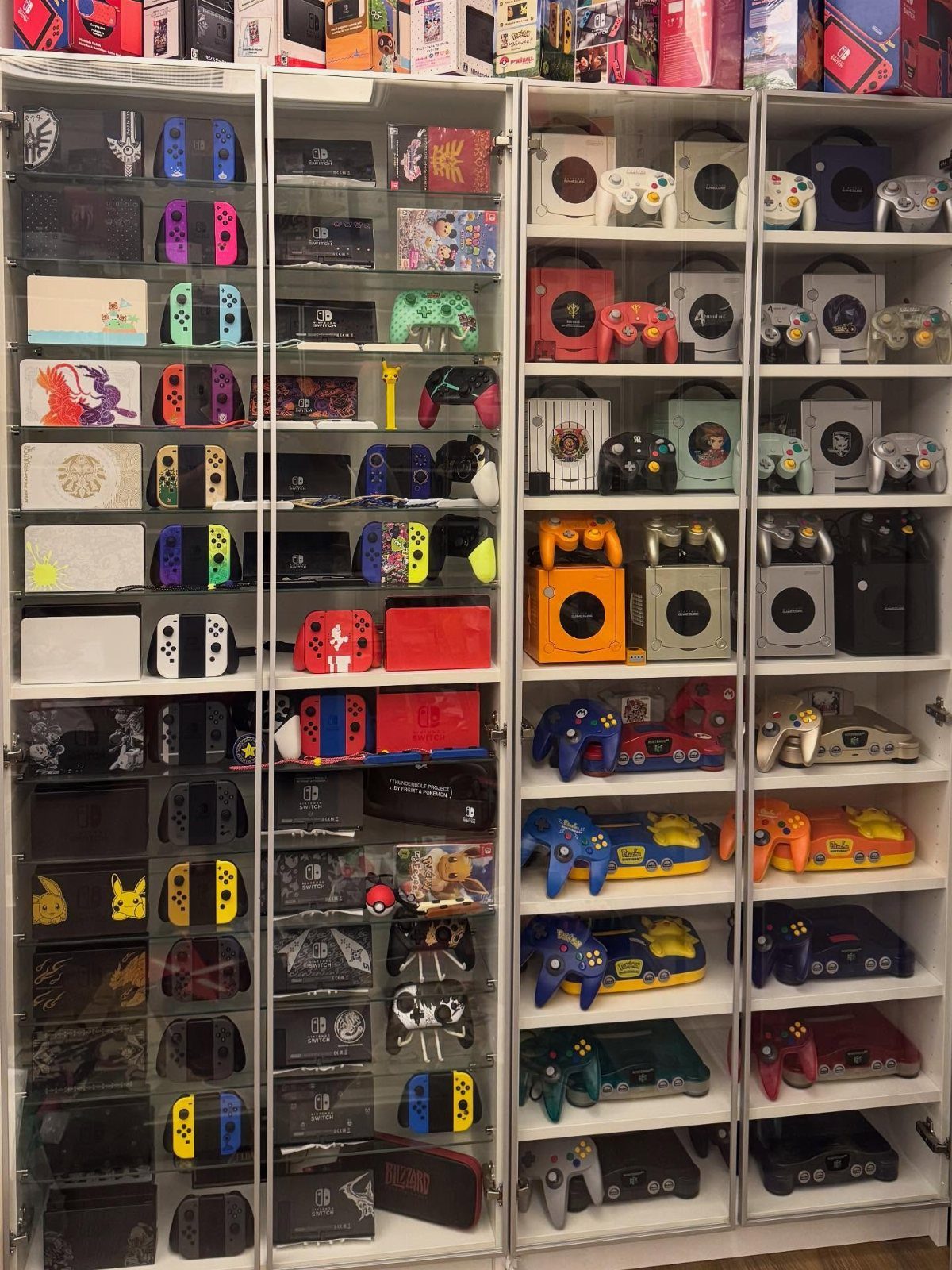 White display cabinets showcasing a large collection of video game consoles and controllers.
