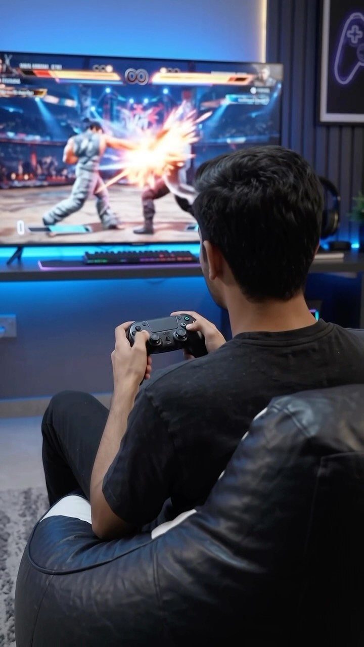 Person sitting in a black leather bean bag playing a video game.