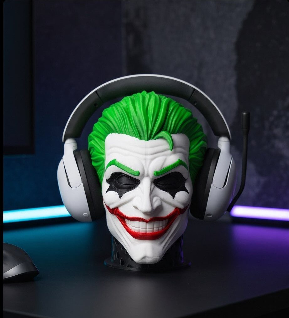 White gaming headset resting on a Joker-themed head stand on a black desk.