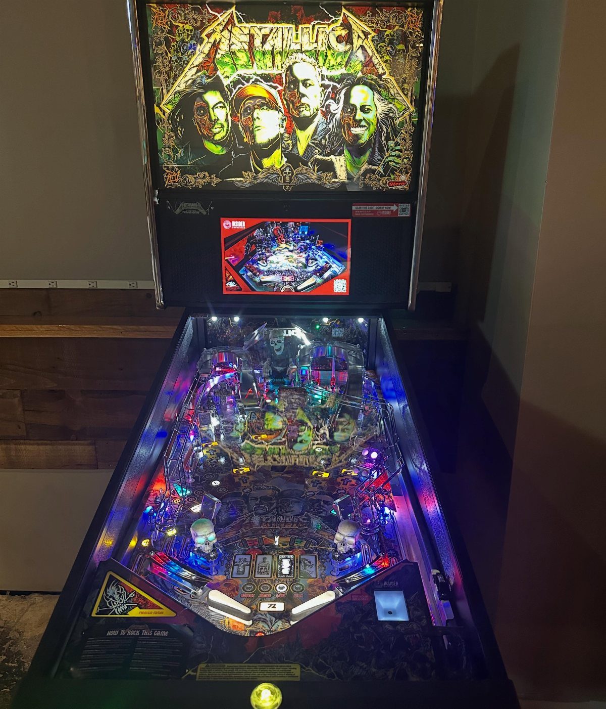 Metallica themed pinball machine with colorful lights and band member artwork on backglass.