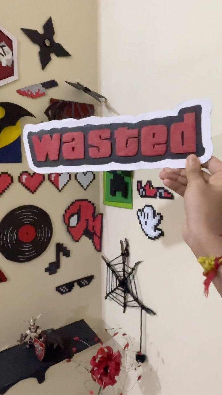 Hand holding a wasted sign against a wall with pixel art decorations