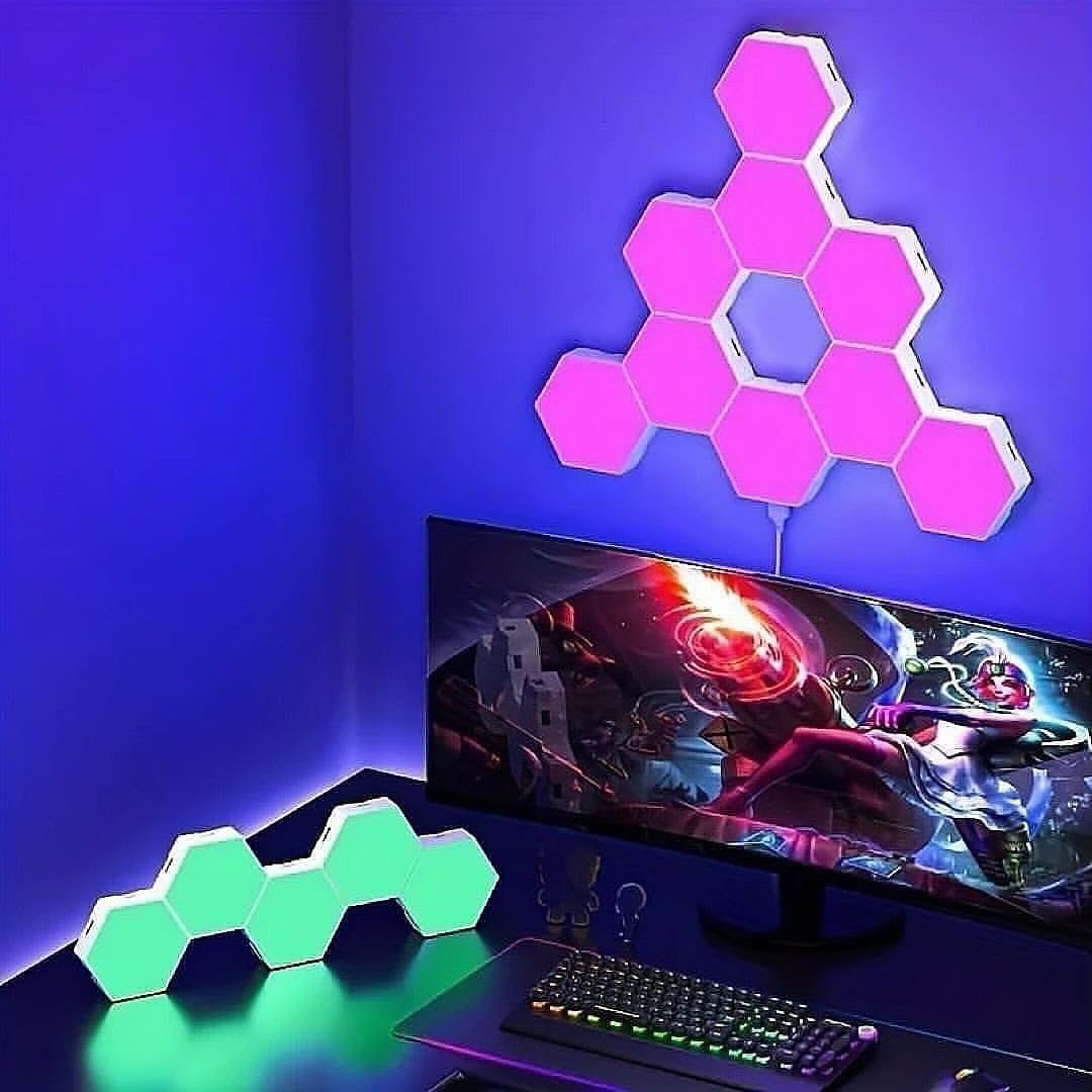 Glowing pink hexagonal wall lights and teal desk lights in a gaming room.