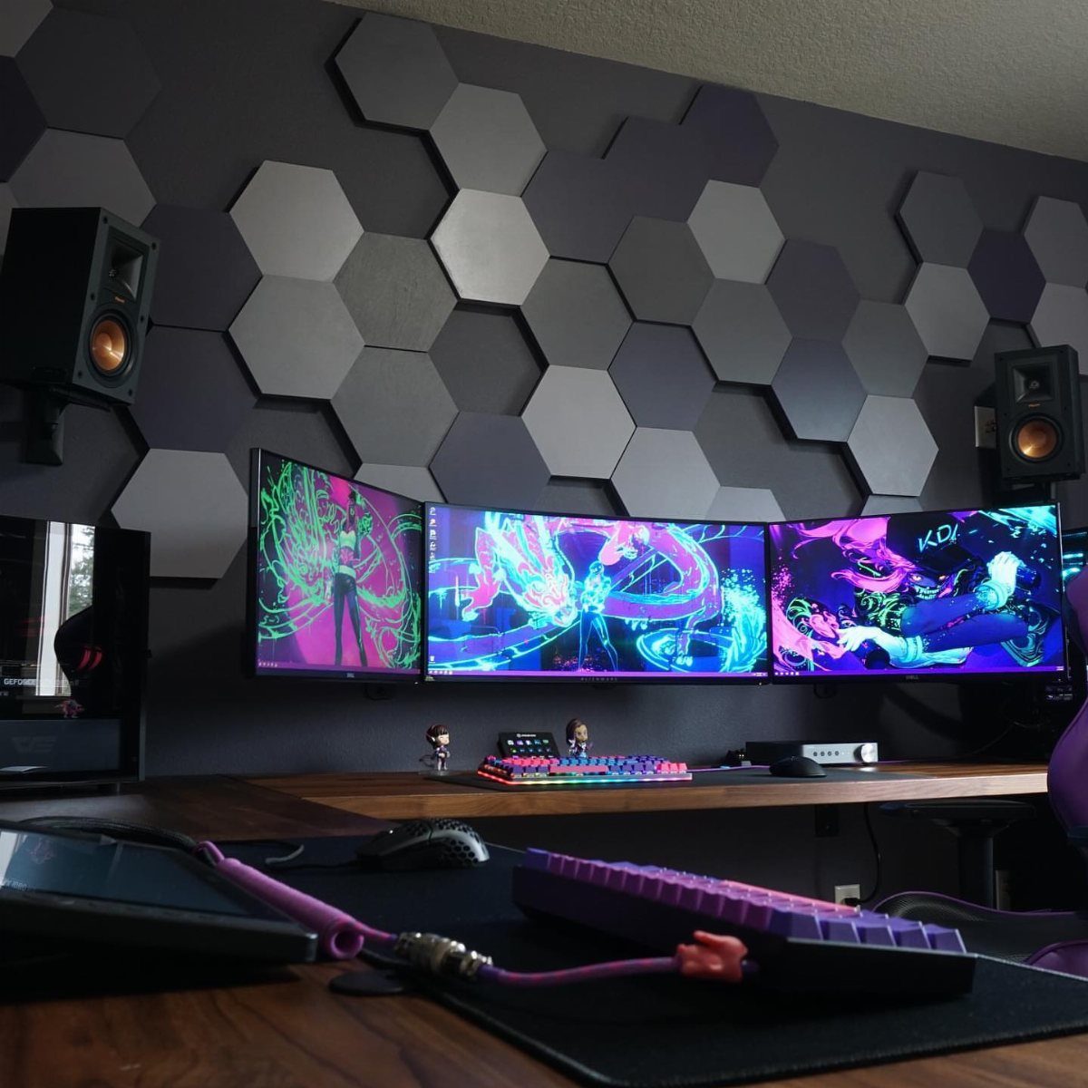 Gaming setup with three monitors and grey hexagonal acoustic panels on the wall