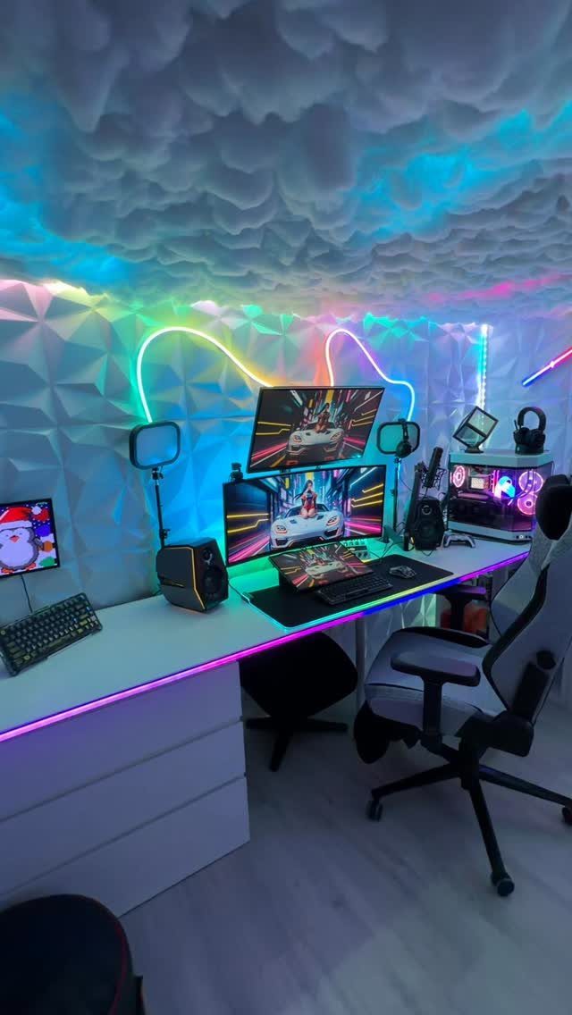 Gaming room with neon lights, cloud ceiling, dual monitors, and a white desk.