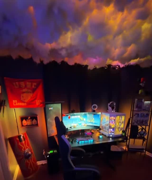 Gaming setup with a custom cloud ceiling illuminated by colorful purple and orange lights.