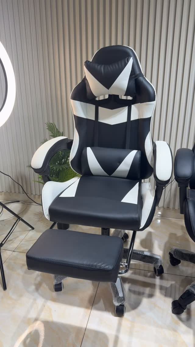 Black and white gaming chair with footrest against a white ribbed wall.