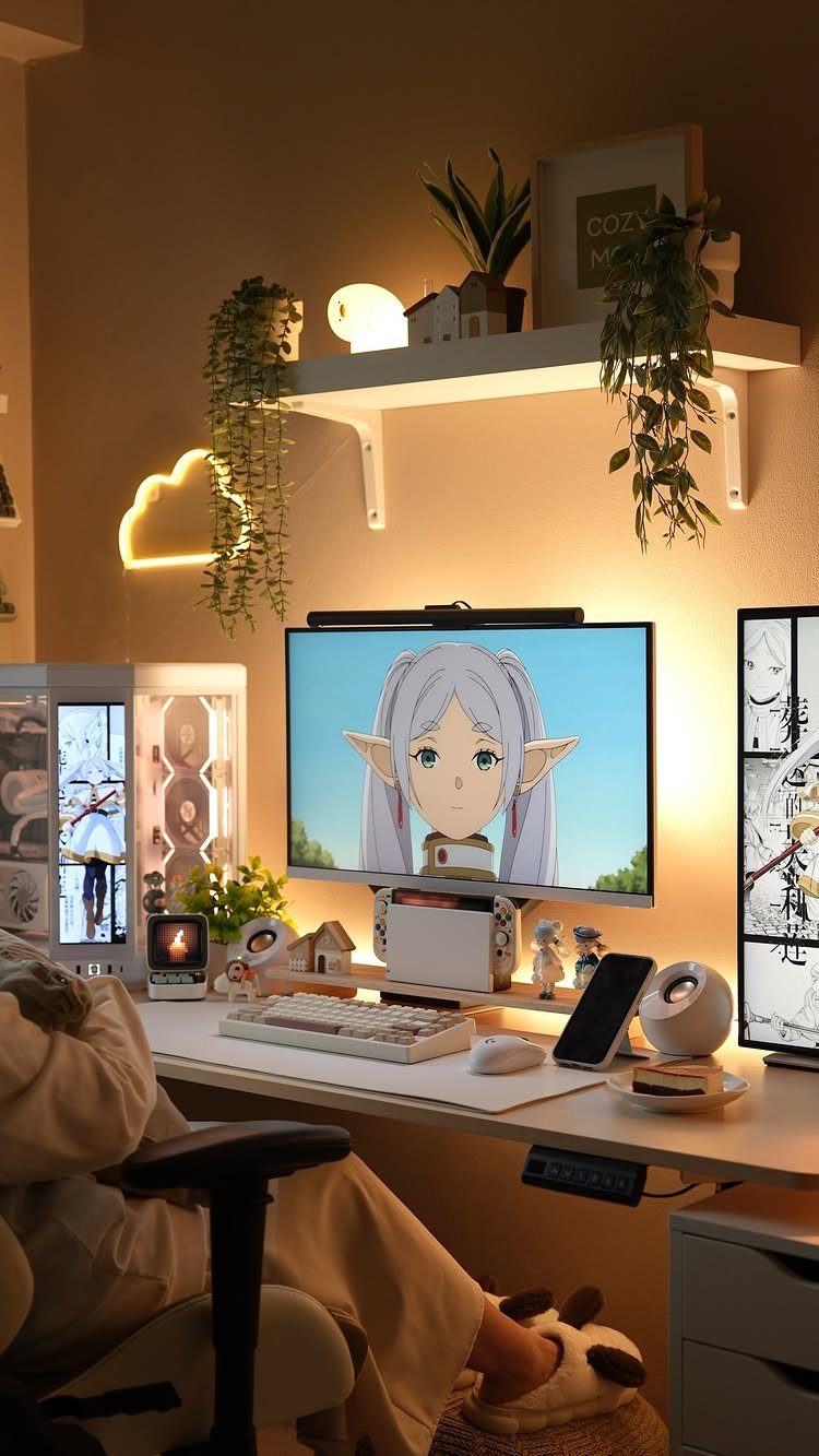 Gaming desk with anime character on monitor, neon cloud light, and hanging plants.