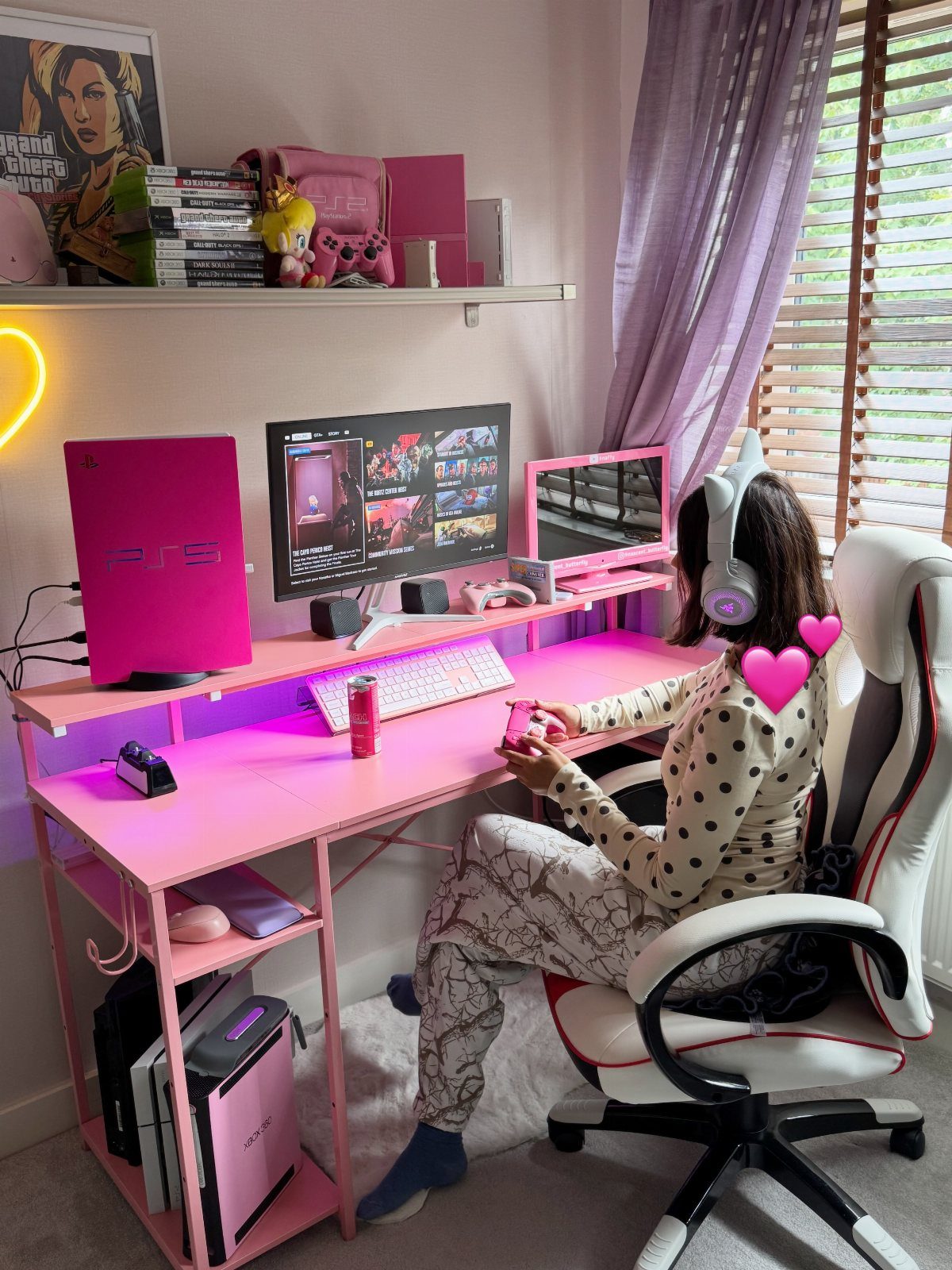 Person gaming at a pink desk with pink PC, keyboard, and monitors.