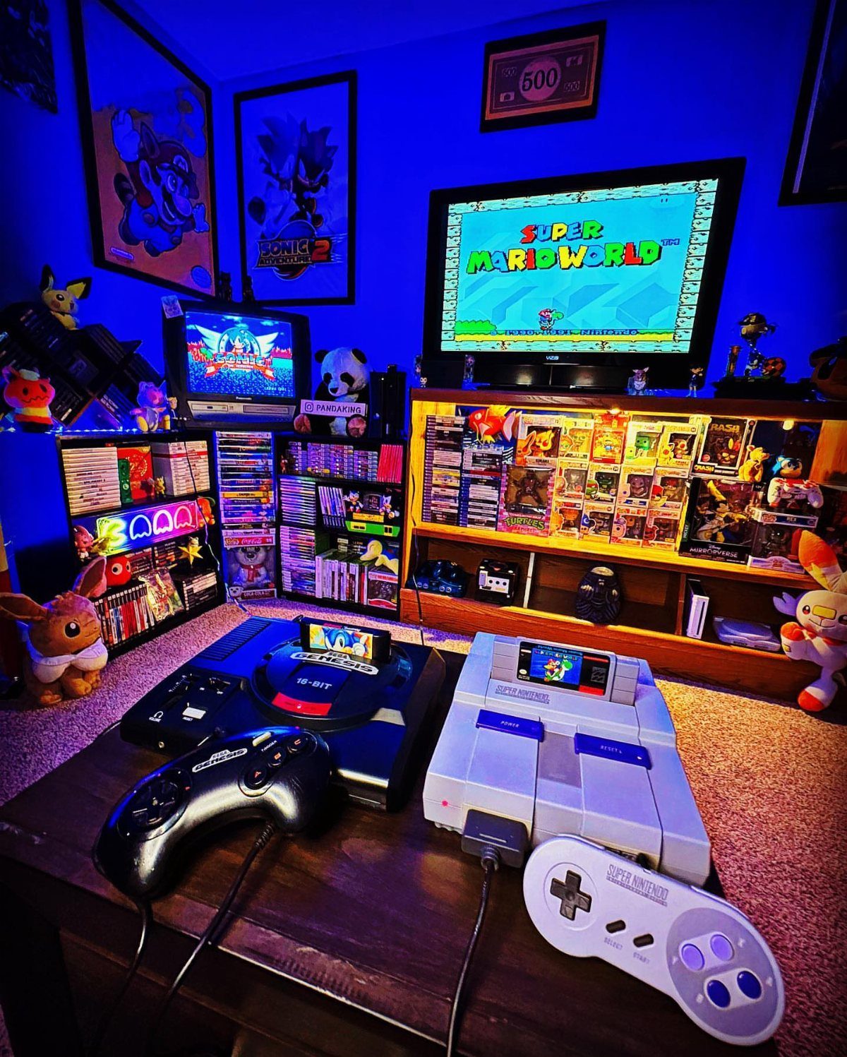 Retro gaming consoles and controllers on a table with Super Mario World on screen.