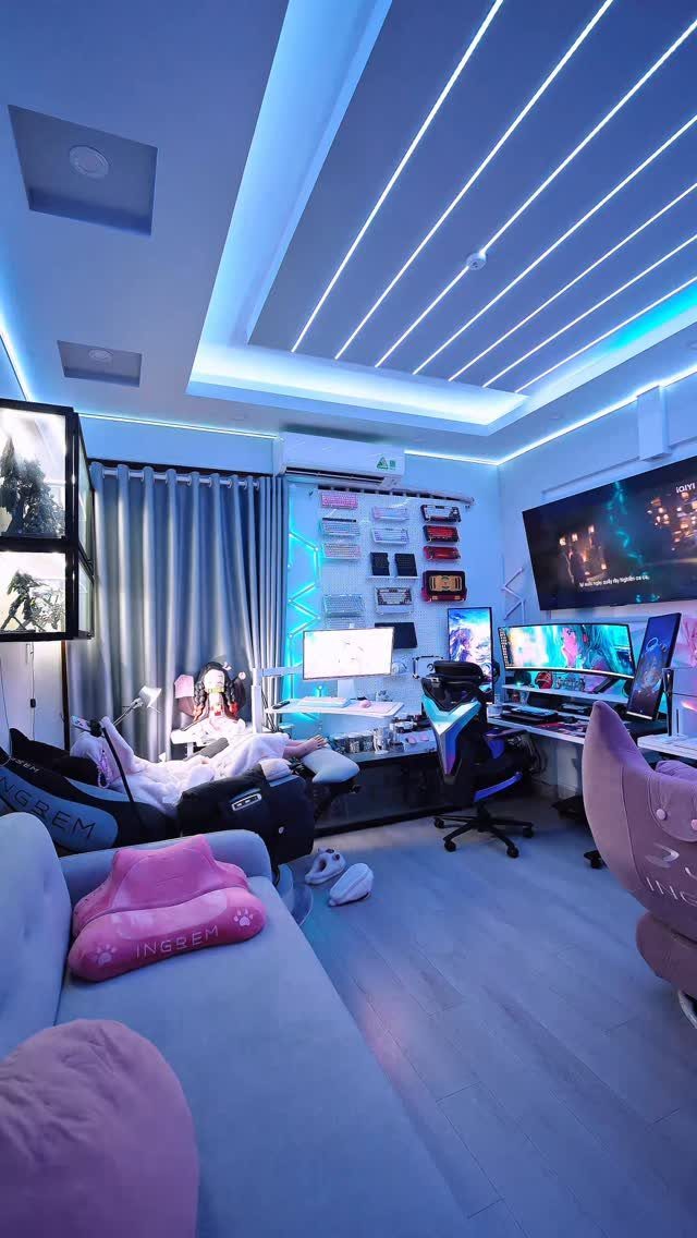 Modern gaming room with blue LED lighting, multiple monitors, and a gaming chair.