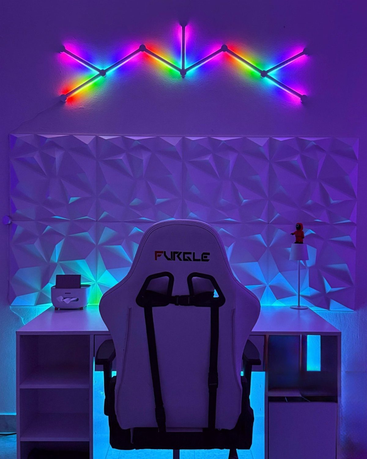 Gaming setup with 3D geometric white wall tiles and rainbow LED lighting.