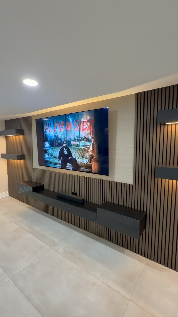 Modern TV wall panel with vertical wooden slats and a dark floating console.