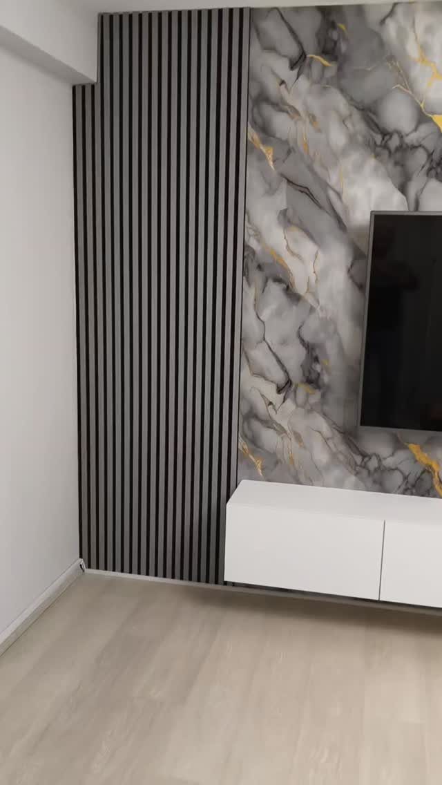 Modern TV unit with marble-patterned wall panel and grey vertical wooden slats.