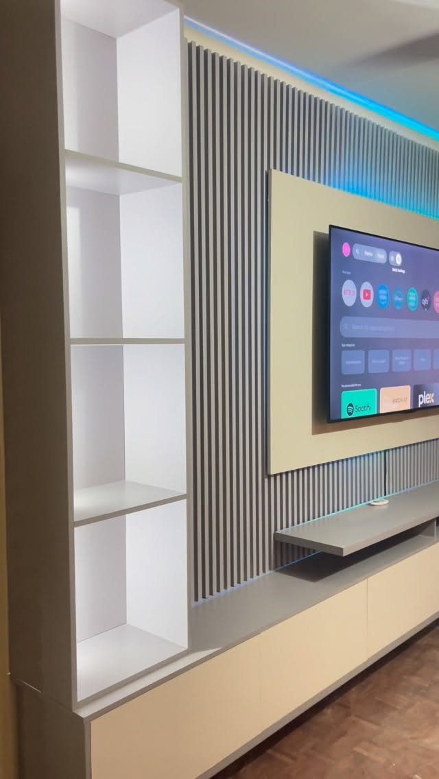 Wall-mounted floating TV unit with slatted grey background and blue LED accent lighting.