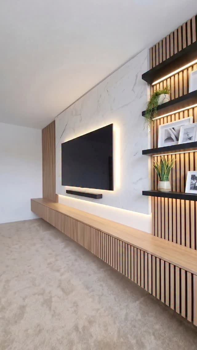 Wall-mounted TV with white marble background and light vertical wood slat accents.