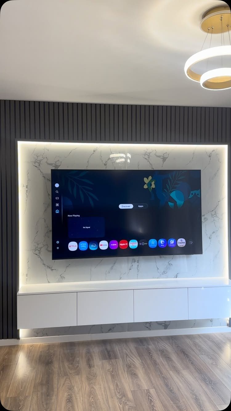 Flat-screen TV on a marble panel with dark grey vertical wood slat walling