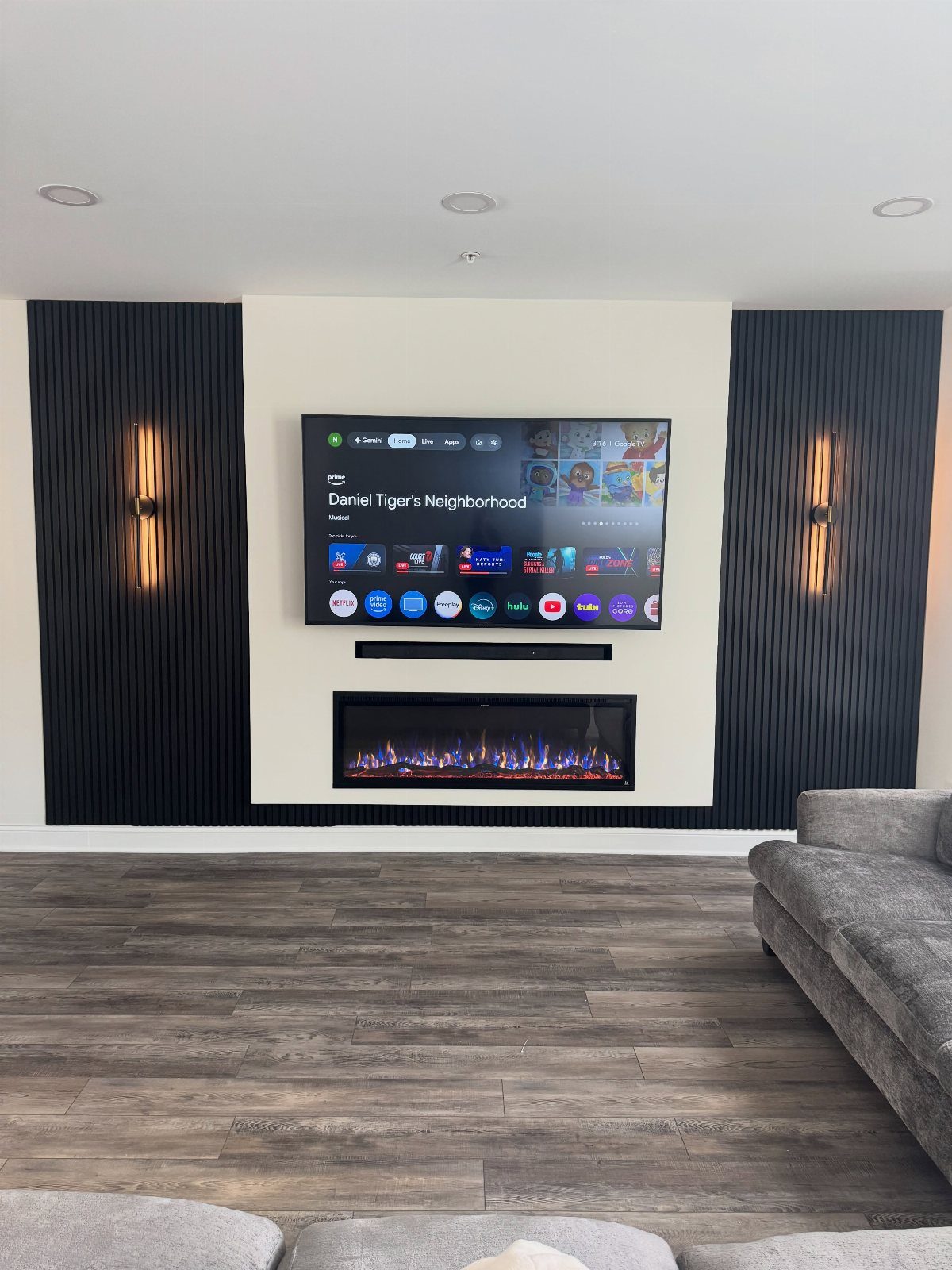 Wall-mounted TV and fireplace flanked by dark slatted wood paneling with warm lighting.